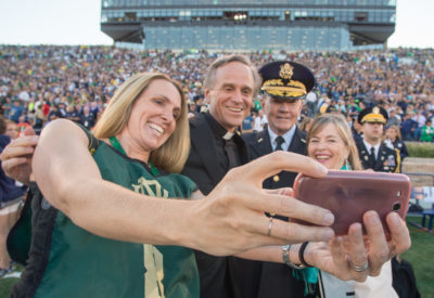 Chairman of the Joint Chiefs of Staff Gen. Martin E. Dempsey, his wife Deanie, Rev. John I. Jenkins, C.S.C., president of Notre Dame University, and a military spouse take a selfie on the field before a football game at Notre Dame Stadium in South Bend, Ind., Sept. 6, 2014. DoD Photo by Mass Communication Specialist 1st Class Daniel Hinton.
