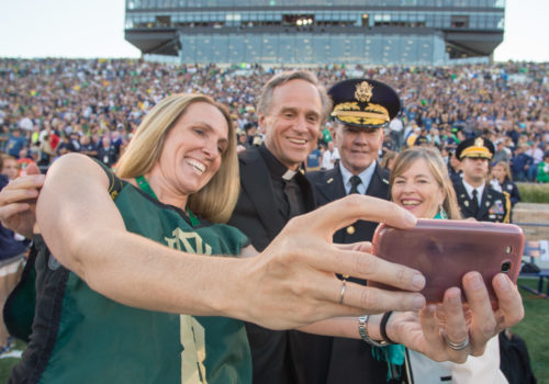 Chairman of the Joint Chiefs of Staff Gen. Martin E. Dempsey, his wife Deanie, Rev. John I. Jenkins, C.S.C., president of Notre Dame University, and a military spouse take a selfie on the field before a football game at Notre Dame Stadium in South Bend, Ind., Sept. 6, 2014. DoD Photo by Mass Communication Specialist 1st Class Daniel Hinton.