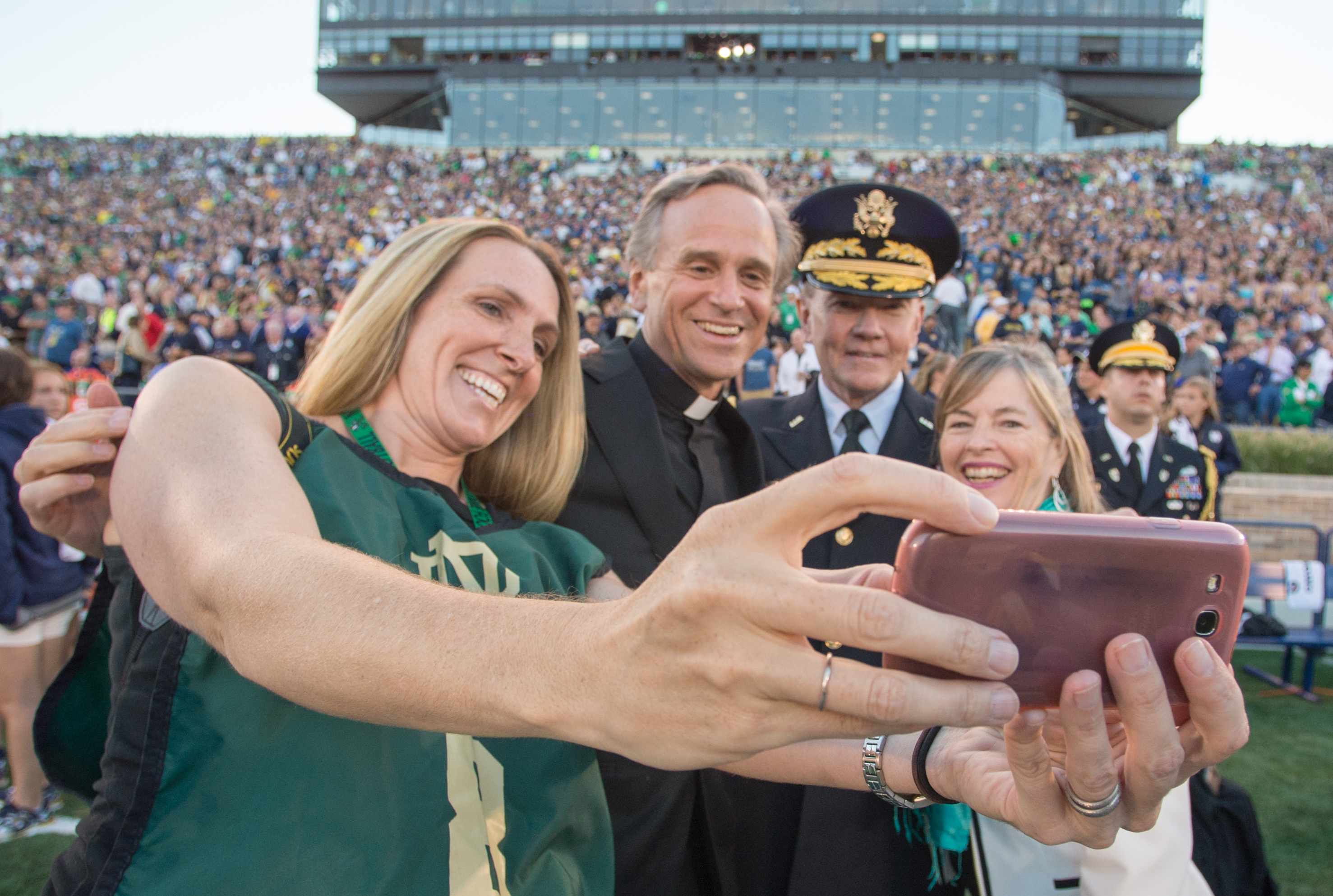 Chairman of the Joint Chiefs of Staff Gen. Martin E. Dempsey, his wife Deanie, Rev. John I. Jenkins, C.S.C., president of Notre Dame University, and a military spouse take a selfie on the field before a football game at Notre Dame Stadium in South Bend, Ind., Sept. 6, 2014. DoD Photo by Mass Communication Specialist 1st Class Daniel Hinton.